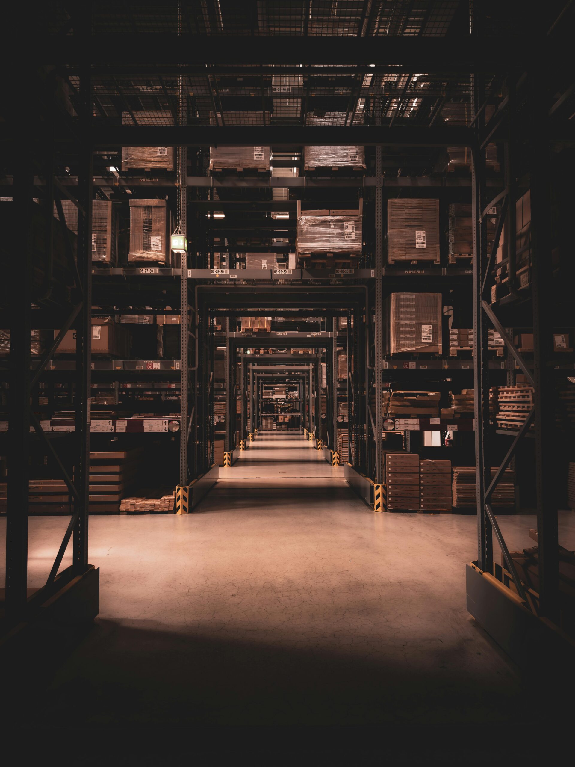 Dimly lit warehouse aisle in Berlin filled with large shelves and boxes, showcasing industrial organization.